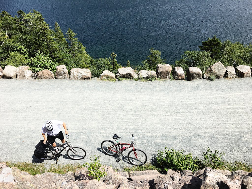 Aerial view of a cyclist resting beside a bike trail near Bar Harbor, ME, by scenic water.